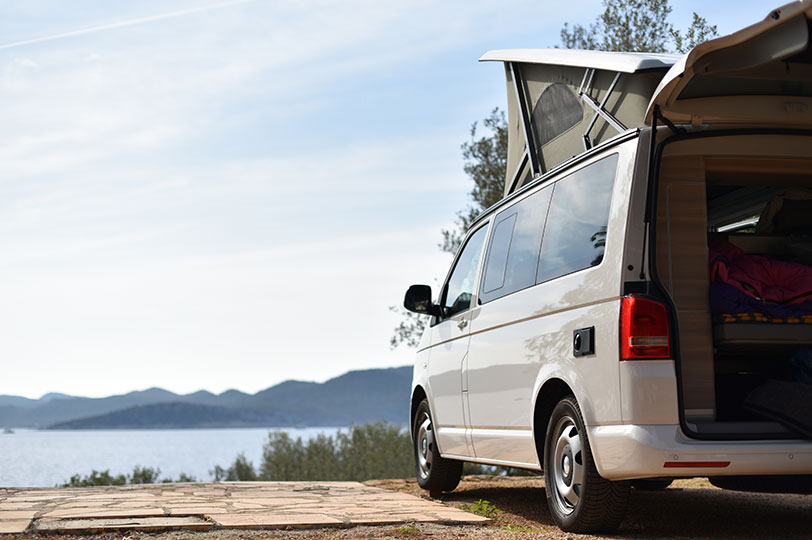 Vw Campervan Parked overlooking a lake with the pop top open and boot door open.