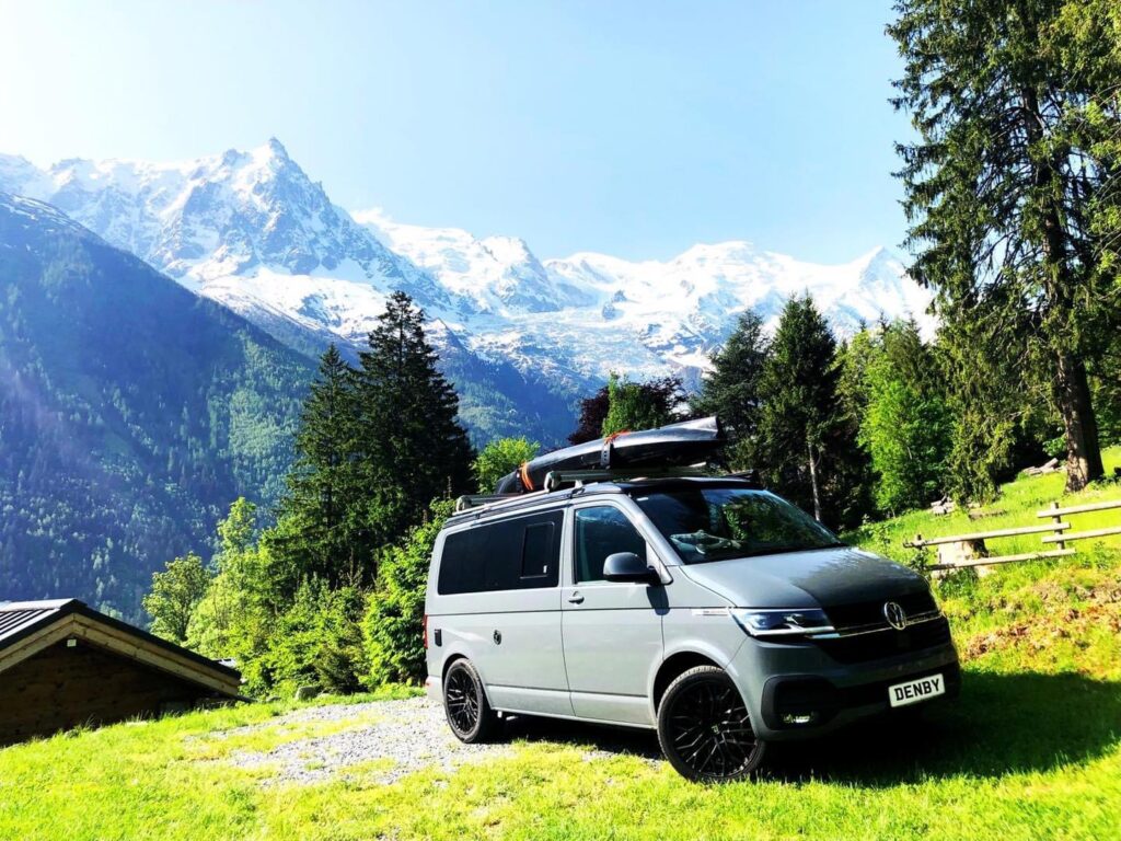 vw camper parked in a field near some mountains