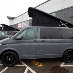 side shot of a T6.1 Volkswagen Transporter Highline Campervan in Pure Grey in the rain with a popped top and additional campervans behind the front van