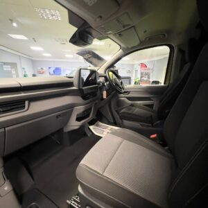 Wide-angle view of the Deluxe SWB - 2025 ALL-NEW Volkswagen Transporter T7 DSG Auto Commerce Plus Campervan interior from the passenger side, showing dashboard, steering wheel, front seats, and infotainment screen in Warm Green.