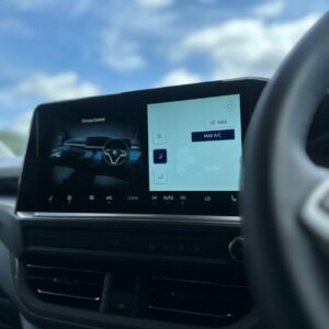 A close-up of the Deluxe SWB - 2025 ALL-NEW Volkswagen Transporter T7 DSG Auto Commerce Plus Campervan’s digital climate control screen, dashboard, and steering wheel with blue sky and clouds visible through the windshield.